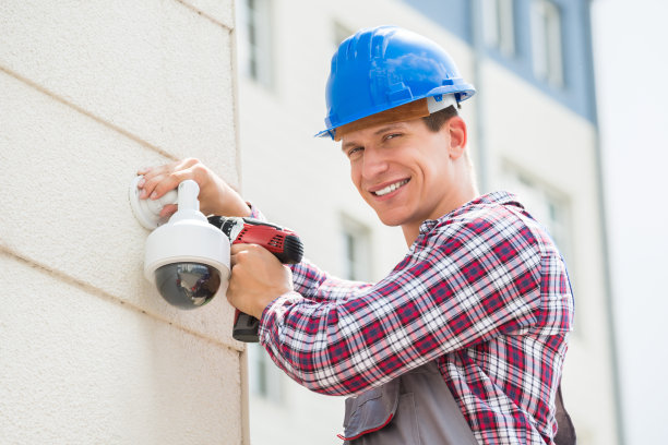 正在墙上安装摄像机的年轻男性技术员图片下载