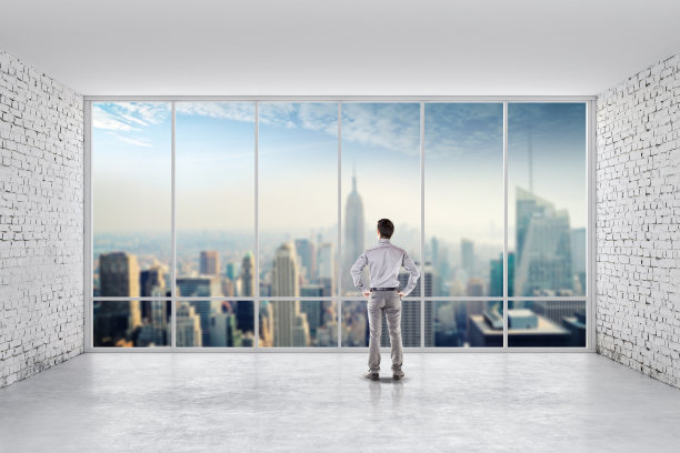 一个商人站在一间明亮、干净、有大窗户的房间里图片下载