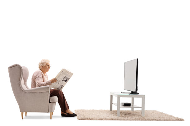 一位老妇人在电视机前看报纸图片下载