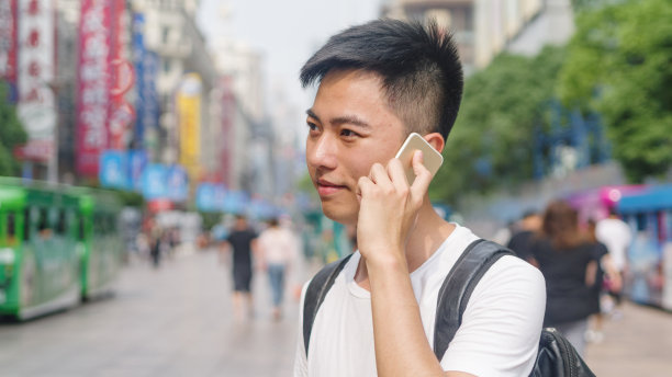 户外半长肖像，年轻的亚洲男子在南京路上讲手机，中国上海。图片下载