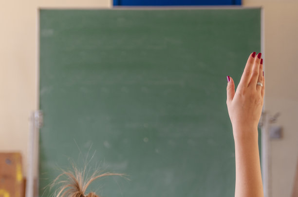 快乐的女孩在教室里举起了手。女学生举手。大学生在礼堂上课。在学校教室里举手图片下载