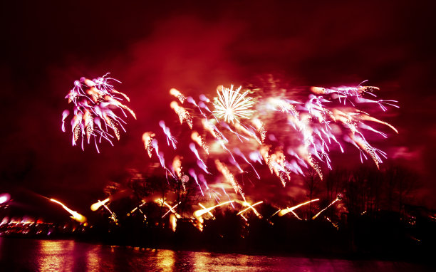 抽象的，模糊的，虚掩风格的彩色烟花照片在一个红色的基调之上的河流图片下载