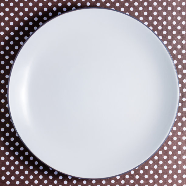 白色空盘子上点棕色纸板。平铺与拷贝空间。图片下载