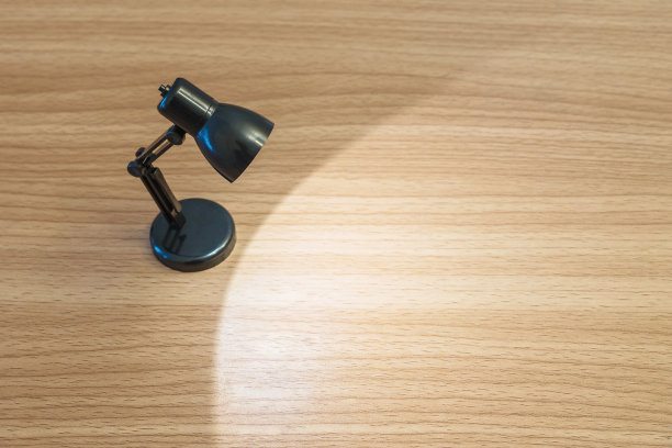 特写黑色小灯与灯光在黑暗的房间木质书桌上有纹理的背景与复制空间图片下载