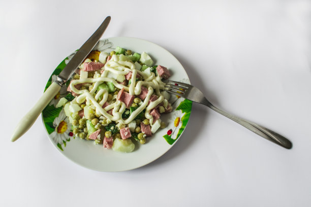 把奥利维尔沙拉放在一个有瓢虫图案的盘子里。接下来是叉子和刀图片下载