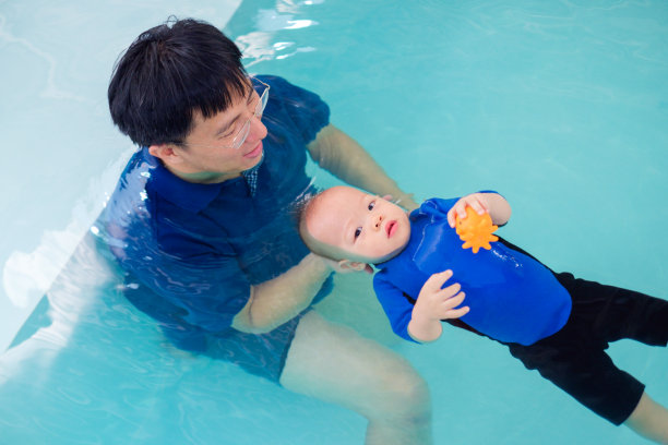 亚洲爸爸带着14个月/ 1岁的可爱的亚洲小男孩去泰国上游泳课图片下载