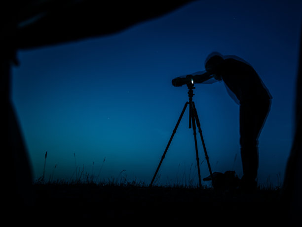 摄影师在拍摄过程中的艺术长曝光照片。多个剪影和一个相机三脚架。晚上从帐篷里看到的景色图片下载