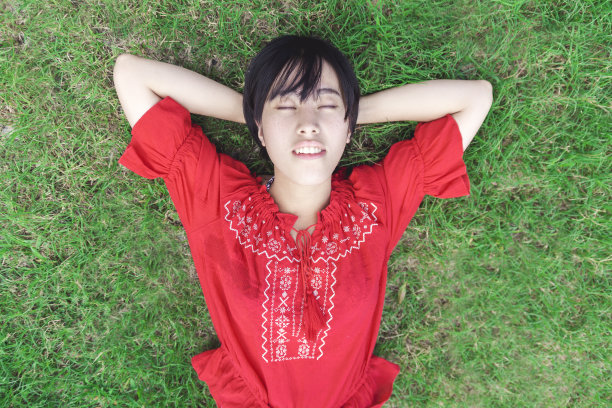 年轻女子躺在草地上睡觉图片下载