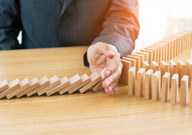 商人用手阻止掉在桌子上的石块素材图片