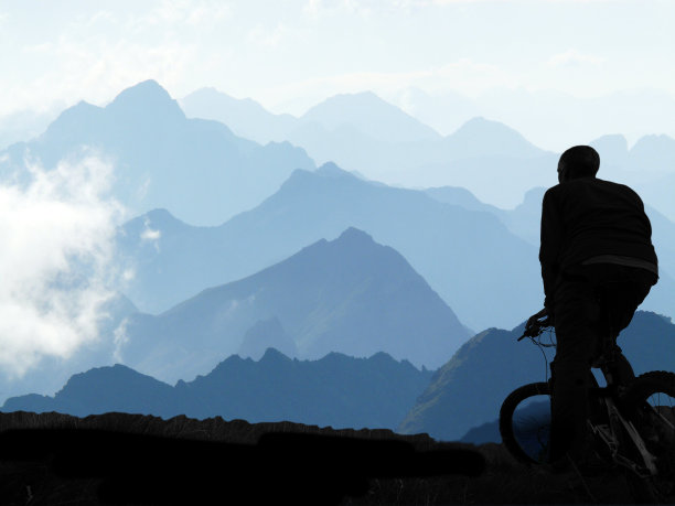 一个骑着山地车的男人站在山脉前图片下载