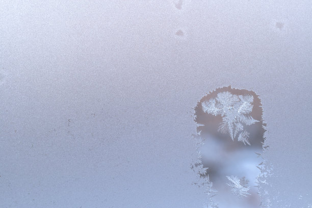 冬天的窗户玻璃结霜，有两片尖尖的雪花的融化点和复制空间。图片下载