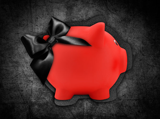 礼品卡标签在一个红色的小猪银行形状与黑色亮丝带蝴蝶结孤立在黑色的背景图片下载