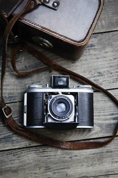老式的复古胶片模拟相机和皮带袋(皮箱)在复古木板上。图片下载