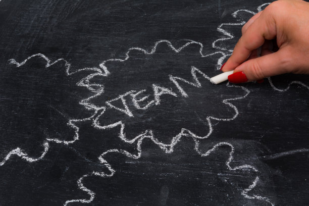 一个女人在黑板上画着团队合作的齿轮图片下载