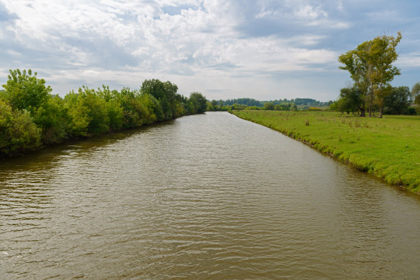 多云天气下树木丛生地区的一条河图片下载