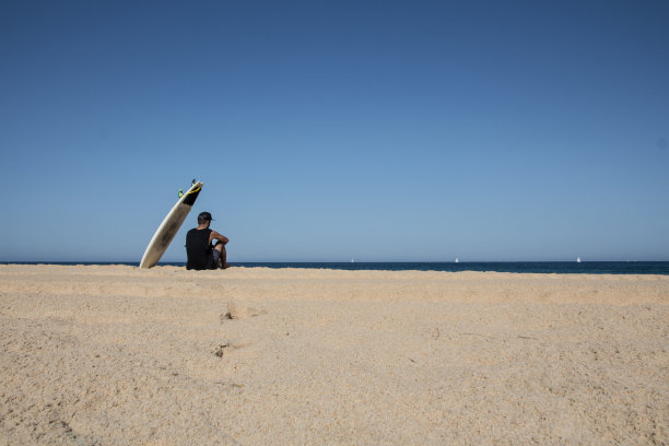 冲浪者坐在冲浪板的阴影下素材图片