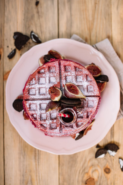 美味的粉红色华夫饼，奶油芝士馅，无花果和巧克力饼干在上面，质朴的旧木头桌子的背景图片下载