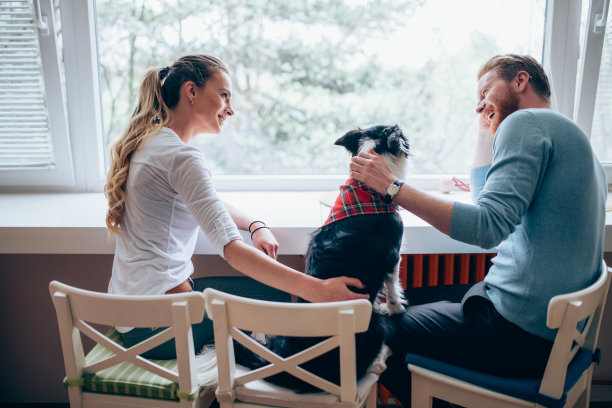 一对美丽的夫妇在家里放松，爱护他们的狗图片下载