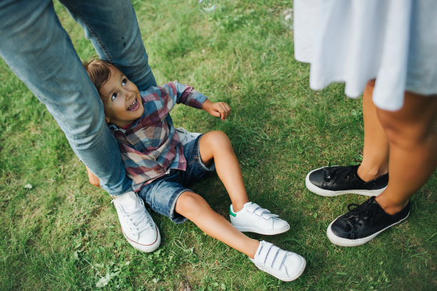 男人女人和孩子的腿在绿草地上图片下载