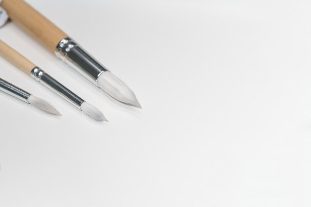 三种不同的白色画笔在软木板背景与复制空间图片下载