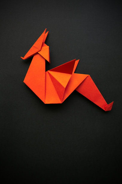 红纸折叠折纸多边形几何龙在黑色的背景。空白区域用于复制，文本，字母。垂直明信片模板。图片下载