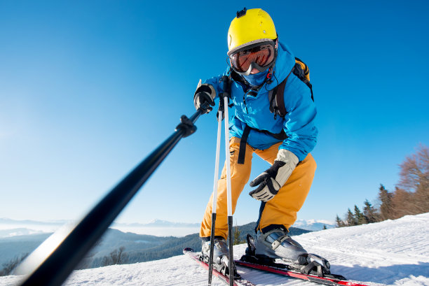 一名专业滑雪者用单脚架在山顶山坡上摆姿势自拍的低角度镜头，copyspace滑雪度假区休闲旅游旅游度假极度肾上腺素图片下载