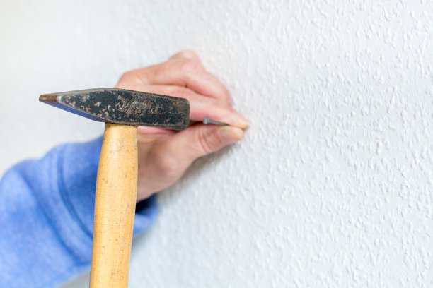 把钉子钉进白色的墙上图片下载