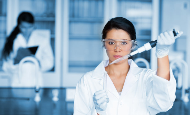 使用大型吸管和试管工作的严肃的化学家图片下载