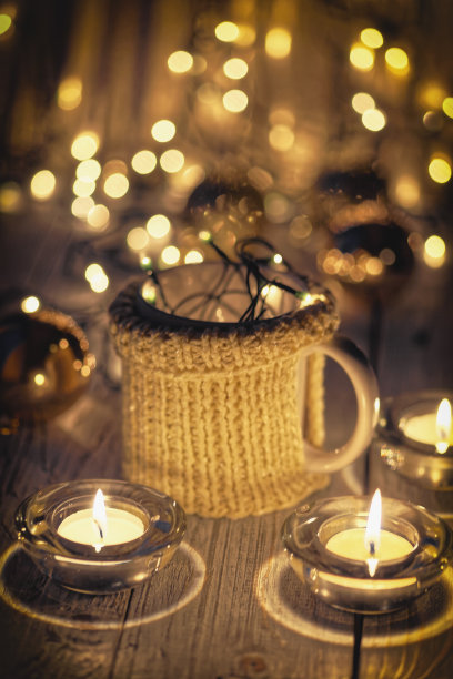 陶瓷时尚的杯子在毛衣和圣诞复古花环的散景灯背景。景深浅。彩色照片图片下载