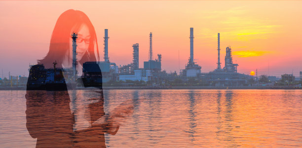 双重曝光的提炼厂和女商人持有和看平板。图片下载