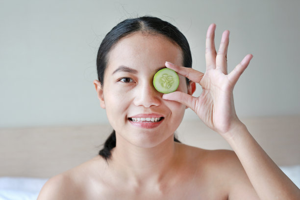 一个年轻漂亮女人的肖像，眼睛上放着黄瓜片。图片下载