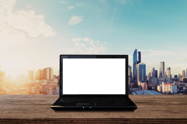 笔记本电脑的空白白色屏幕上的木桌与城市的日出。剪切路径计算机屏幕图片下载