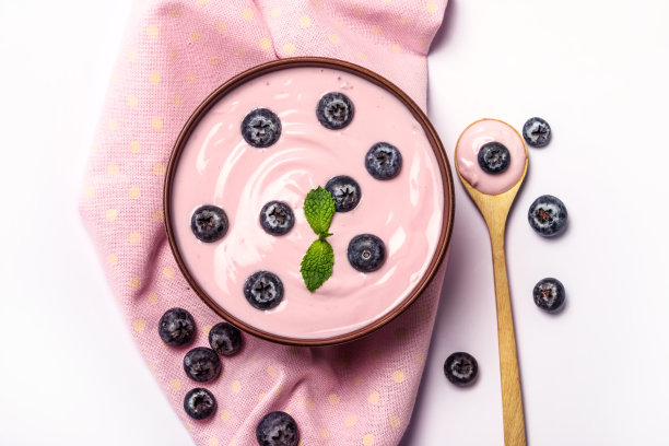 近距离粉红色奶油自制蓝莓水果酸奶与新鲜的绿色薄荷叶在白色的背景，俯视图或头顶拍摄图片下载
