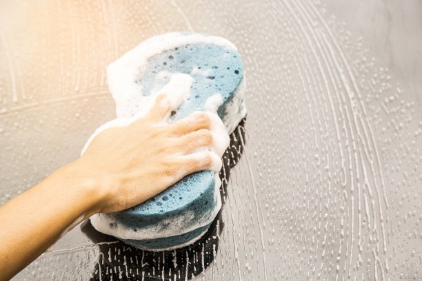 女手拉手用蓝色海绵洗车。概念洗车干净。图片下载