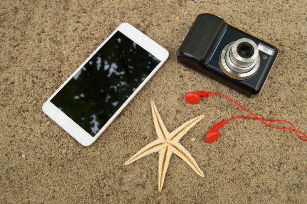 在沙滩上规划旅行和度假的概念。俯视图智能手机，相机，海星，耳机图片下载