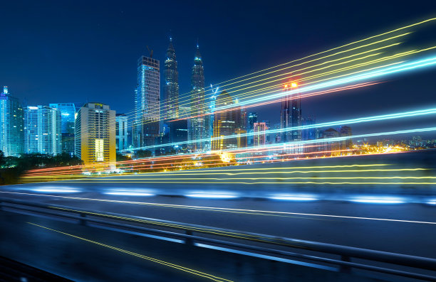 从立交桥的一边看，模糊的运动效果与光的轨迹和美丽的城市天际线背景。图片下载