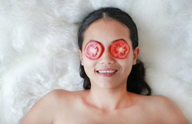 眼睛里放着一片西红柿的年轻女子，护肤理念。图片下载
