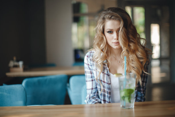 美丽的年轻女子坐在咖啡馆喝着莫吉托鸡尾酒图片下载