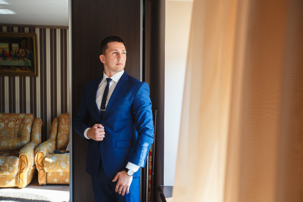 新郎在家里穿西装。可爱的新郎为摄影师摆姿势图片下载