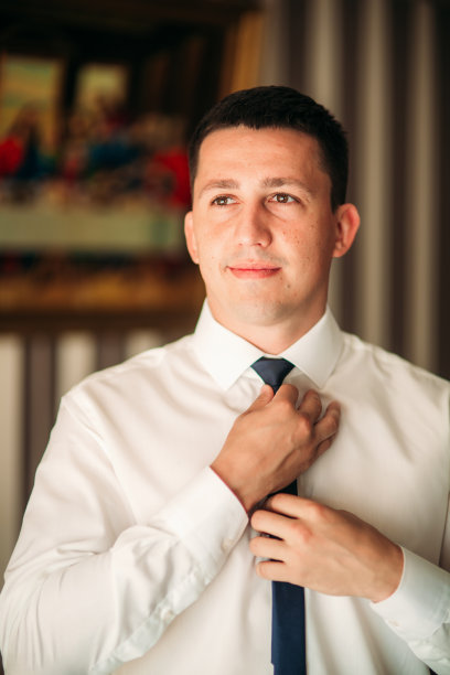 新郎在家里穿西装。可爱的新郎为摄影师摆姿势图片下载