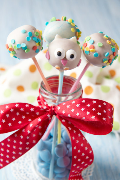 猫头鹰蛋糕棒棒糖，瓶子里有五颜六色的糖屑，蓝色的smarties，是给孩子们吃的甜食图片下载