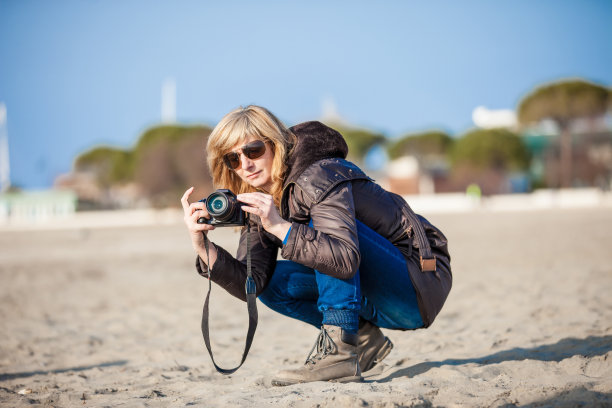 一个女人在深秋的海滩上拍照图片下载