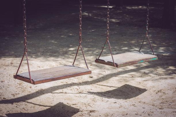 两个带链条的木椅秋千挂在操场上，进入公园。图片下载