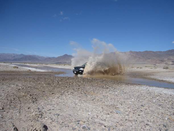 死亡谷的景观。汽车4x4穿越一条河。图片下载