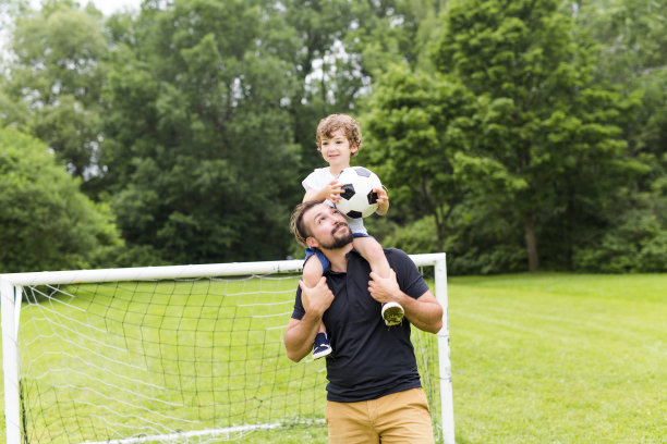 父亲和儿子在足球场踢足球图片下载