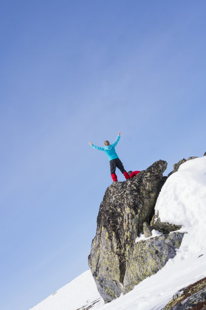 黄金和光荣，资深女性，不列颠哥伦比亚省滑雪者在挪威哈当厄飞机的荒野岩石上拍照图片下载