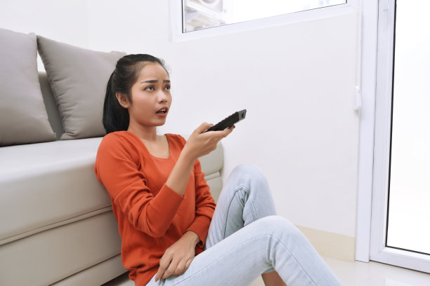 年轻的亚洲女人边看电视边坐着图片下载