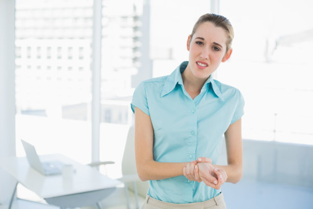 年轻漂亮的女商人紧握着受伤的手腕图片下载