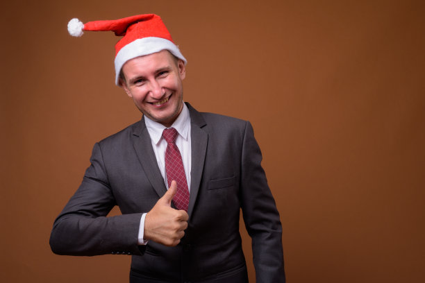 工作室拍摄的商人戴着圣诞帽准备圣诞节的彩色背景图片下载