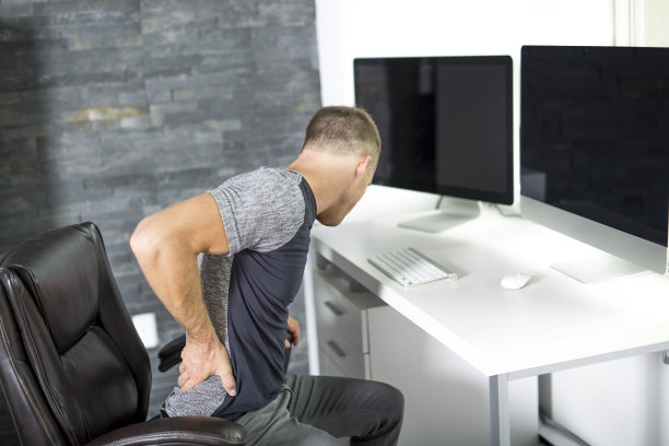 坐在办公室电脑桌前忍受背痛的男人图片下载